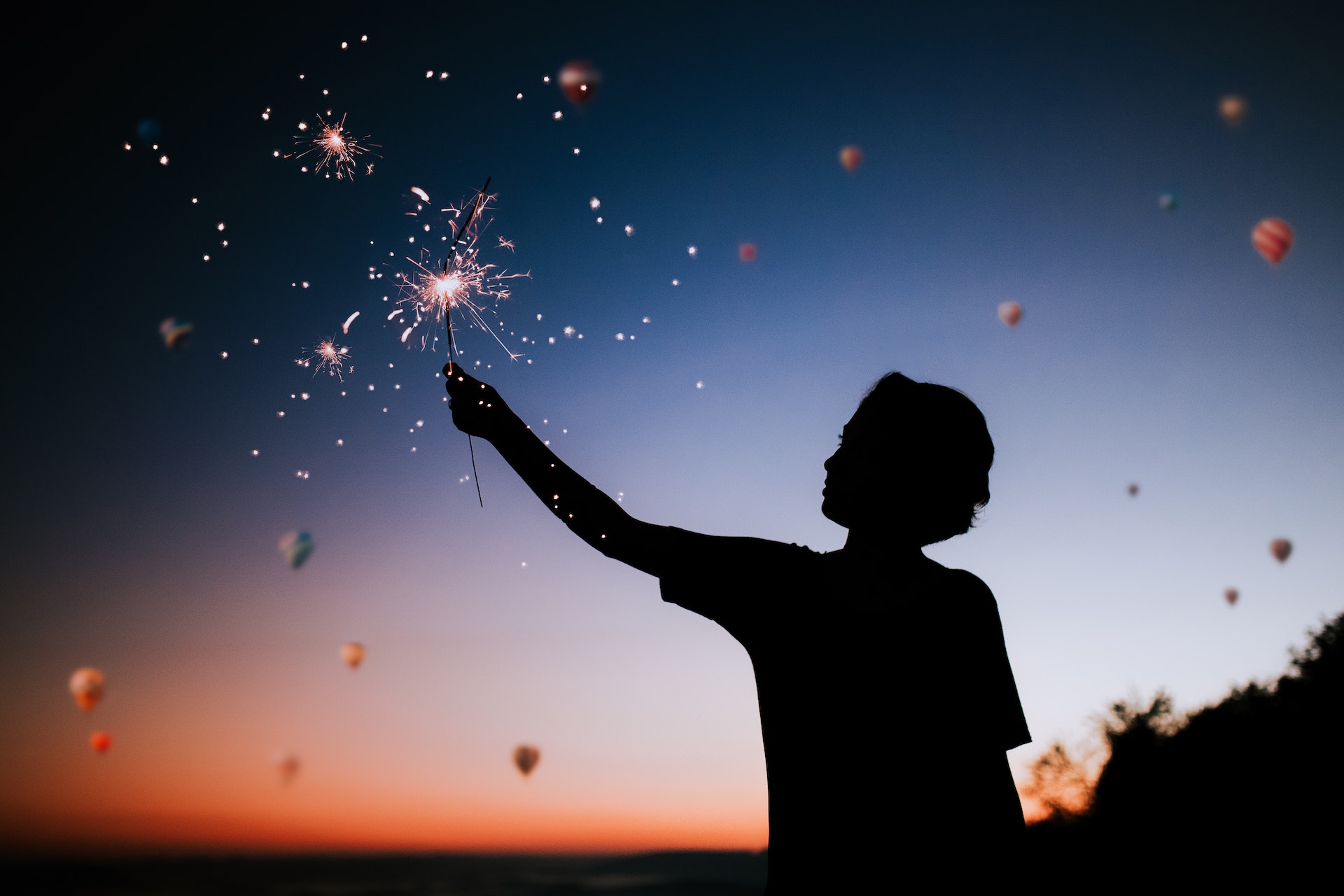 boy holding sparkler firework at night